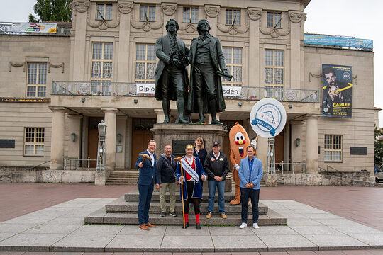 Die Initiatoren und Unterstützer des Wurst- und Spezialitätenmarktes vor dem Goethe- und Schiller-Denkmal in Weimar (v.l.n.r.): Tobias Hinz (Vorstandsvorsitzender des Vereins zur Förderung des Handwerks Thüringen e.V.), Frank Martin (Vorstandsmitglied des Vereins zur Förderung des Handwerks Thüringen e.V.), Thüringer Bratwurstkönig Norbert I, Helgard Anding (Geschäftsführerin des Landesinnungsverbandes des Fleischerhandwerks Thüringen e.V.), Thomas Mäuer (Geschäftsführer der Bratwurstmuseum Betriebs-GmbH), Christian Schwartze (Amtsleiter für Wirtschaft und Märkte Weimar) und Maskottchen „Wursti“.